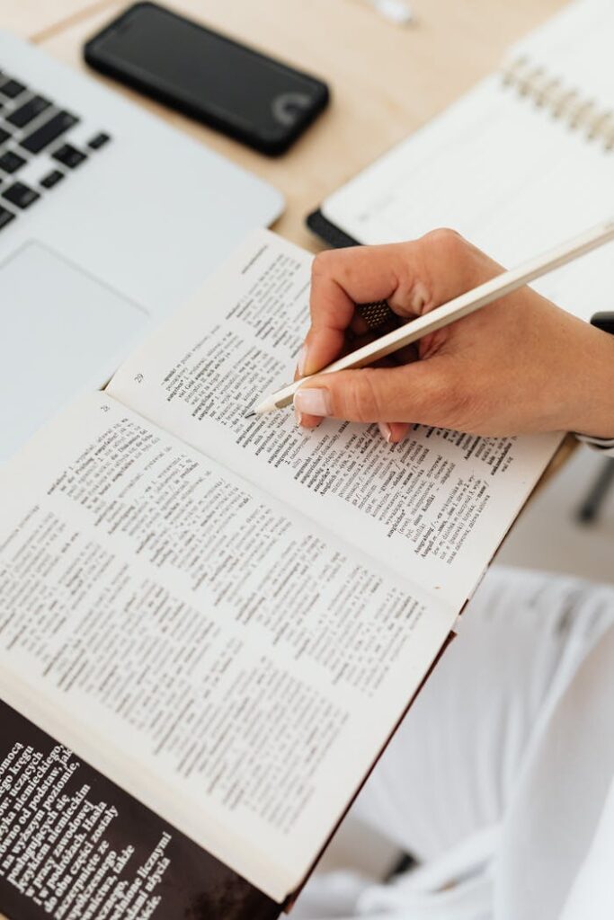 pexels-photo-5238126 Close-up of Woman Sitting at the Desk with a Laptop and Underlining Words in a Book